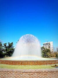 Fountain in park against clear blue sky