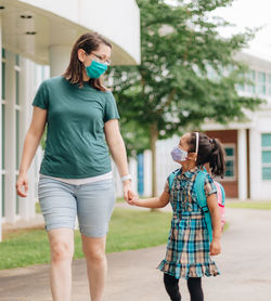 Young millennial mother sending daughter off back to school