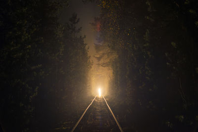 Illuminated railroad tracks against sky