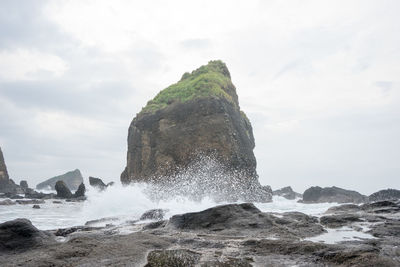 Sea waves splashing on shore against sky