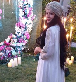 Side view of young woman standing against plants