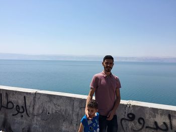 Portrait of young man standing against sea