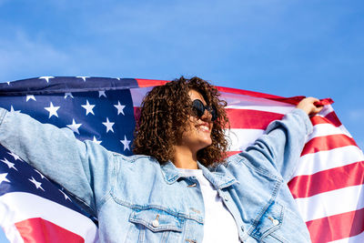 Beautiful woman holding flag celebrating independance us day. candid portrait of woman in sunglasses