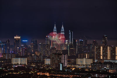 Illuminated buildings in city against sky at night