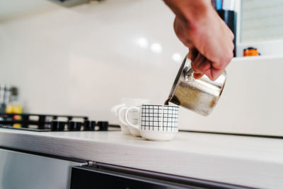 Close-up of hand pouring tea cup