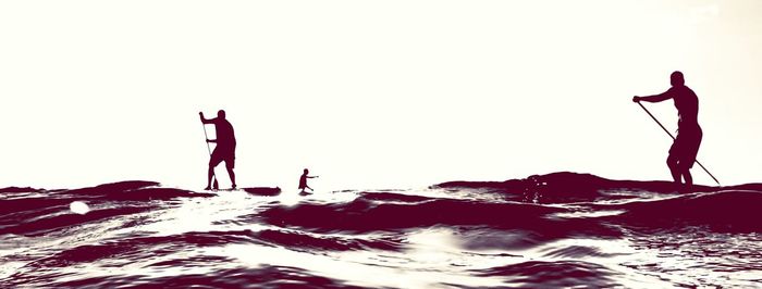 People at sea shore against clear sky