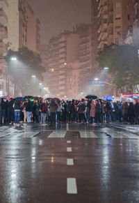Crowd on wet city street at night during rain