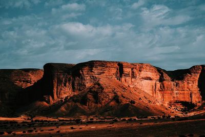 Rock formations on mountain against cloudy sky