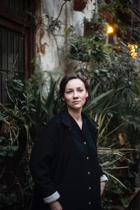 Portrait of young woman standing against plants