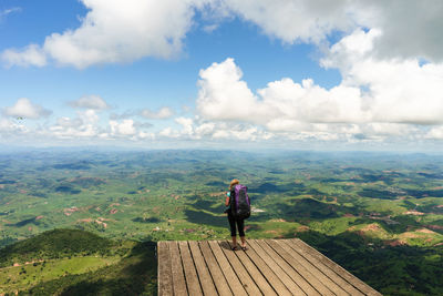 Woman standing on boardwalk against landscape in sunny day