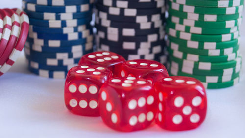 Close-up of red dice and gambling chips on white table