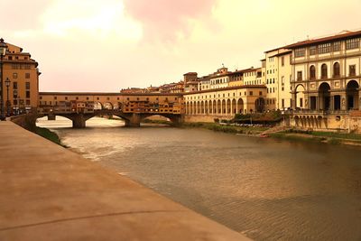 Arch bridge over river against buildings in city