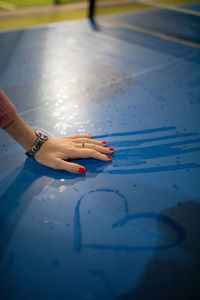 Woman with red nail polish touching wet blue surface