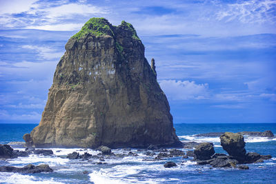 Rock formation on sea shore against sky