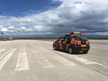 Car on road against cloudy sky