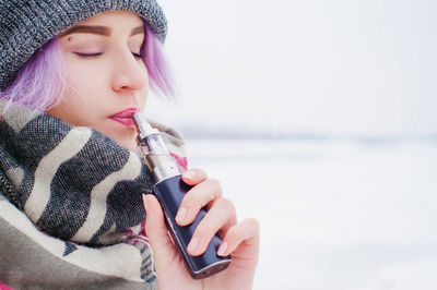 Close-up of young woman holding smart phone while standing on beach