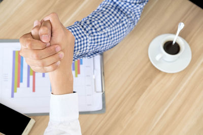 Cropped image of colleagues with holding hands over desk