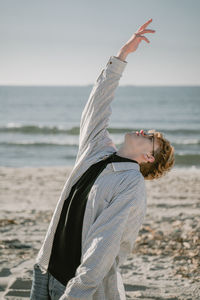 Rear view of woman with arms outstretched at beach