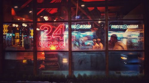 People seen through with window with illuminated reflection