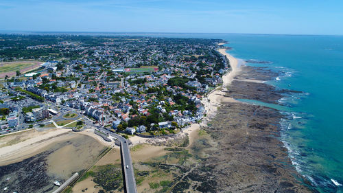 Aerial view of city by sea against sky