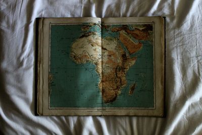 Close-up of world map book on bed sheet