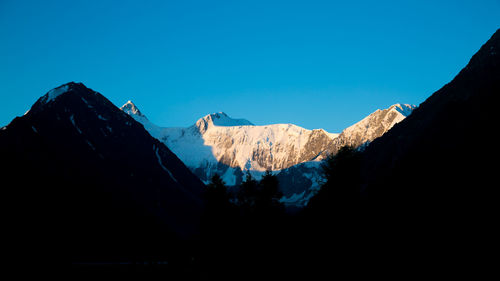 Scenic view of snowcapped mountains against clear blue sky