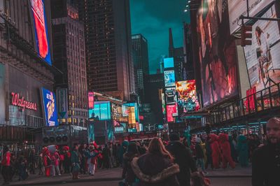 People walking on illuminated street in city at night