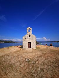 Building by sea against blue sky