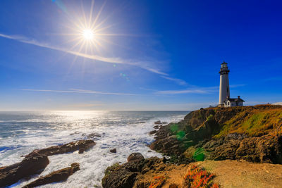 Lighthouse by sea against sky