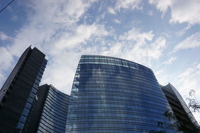 Low angle view of skyscrapers against cloudy sky