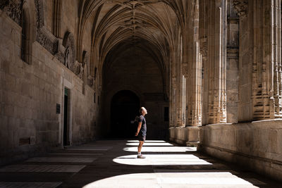 Rear view of woman walking in corridor of historic building