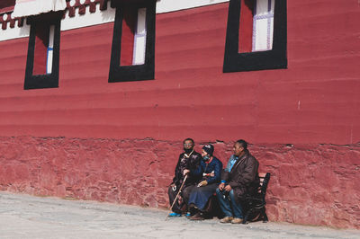 People sitting on brick wall of building