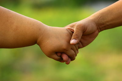 Cropped image of people holding hands outdoors