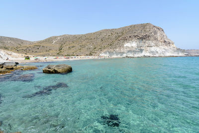 Scenic view of sea and mountains against clear blue sky