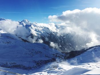 Scenic view of snowcapped mountains against cloudy sky