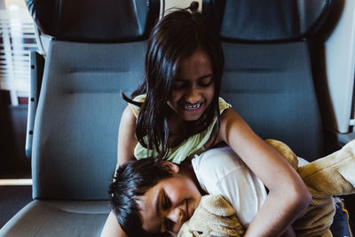 Siblings playing with stuffed toy while sitting in train