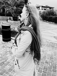 Woman looking away while standing on footpath