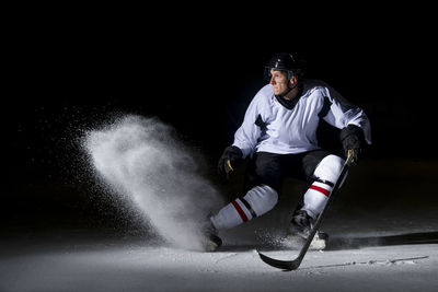 Man playing ice hockey against black background