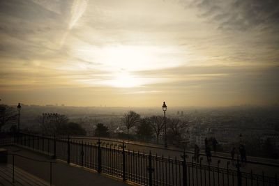 Man standing by railing in city against sky