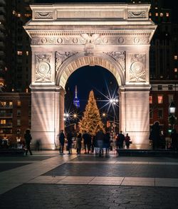 People in front of illuminated gate at night