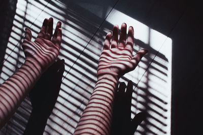 Sunlight falling on cropped hands of woman over tiled floor at home