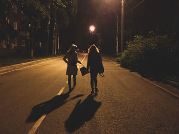 Rear view of women walking on street at night