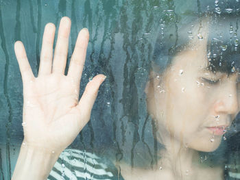 Close-up of woman hand on wet glass