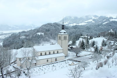 High angle view of snow covered houses and trees against sky