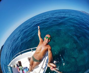 Low angle view of shirtless man sailing in sea against sky