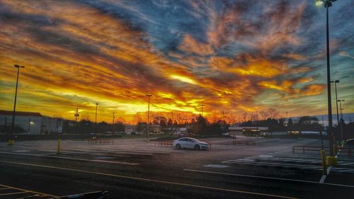 Cars on road against cloudy sky at sunset