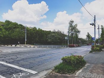 Trees by road against sky