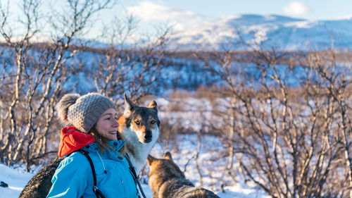 View of a young woman with wolf in snow