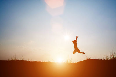 Silhouette boy jumping against sky during sunset