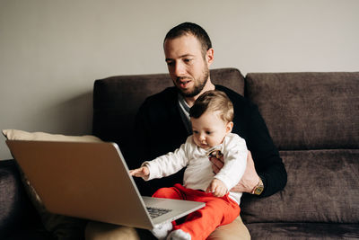 Portrait of man using mobile phone while sitting on sofa at home